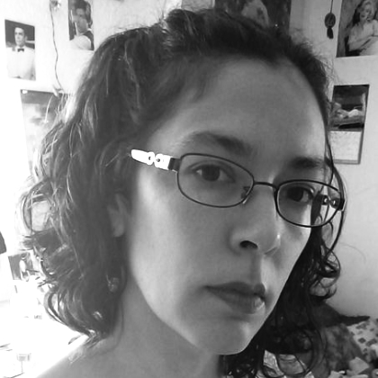 Zdjęcie autora: Cathy Ulrich. Kobieta mieszanej rasy z kręconymi włosami i w okularach, pozująca na tle ściany obwieszonej zdjęciami aktorów